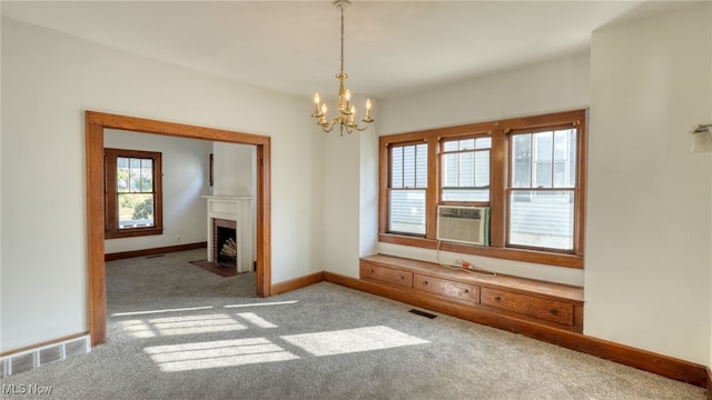 carpeted empty room featuring plenty of natural light, cooling unit, and a notable chandelier