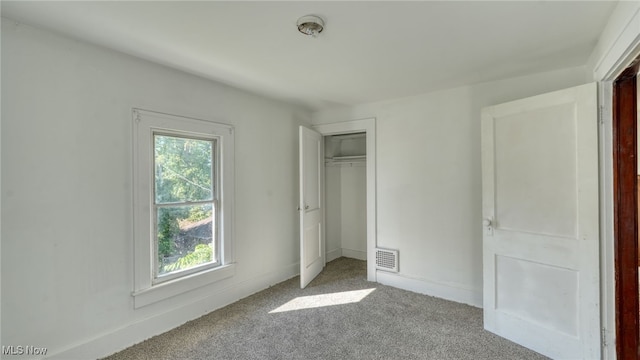 unfurnished bedroom with light carpet, a closet, and multiple windows