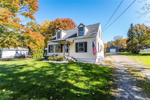 cape cod-style house featuring an outbuilding, a garage, and a front lawn