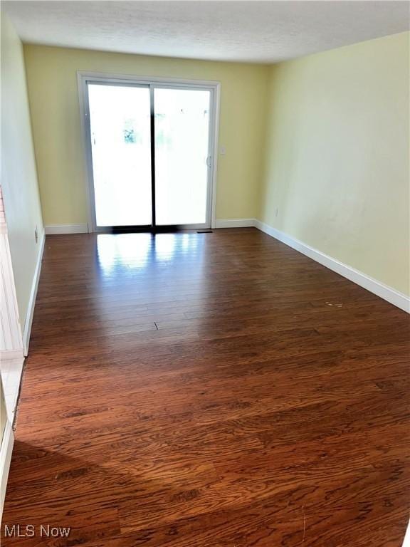 spare room featuring a textured ceiling and dark hardwood / wood-style flooring