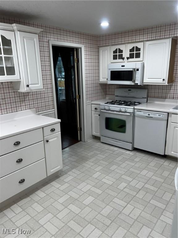 kitchen with white cabinetry, white appliances, and backsplash