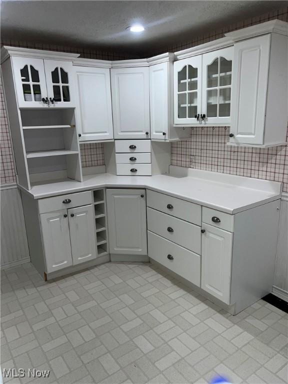 kitchen featuring white cabinetry, a textured ceiling, and tasteful backsplash