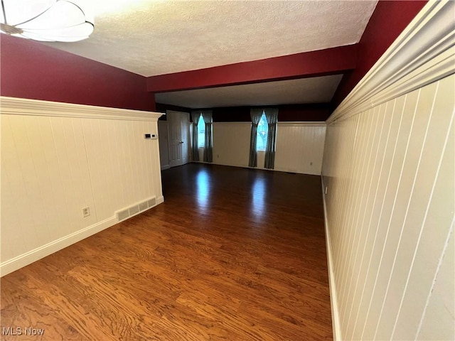 spare room with wood-type flooring, a textured ceiling, and wood walls