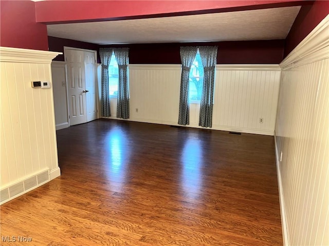 spare room with plenty of natural light, wood-type flooring, and wooden walls