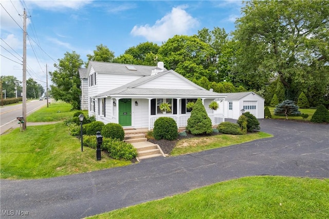 view of front of house featuring a garage, an outbuilding, and a front yard