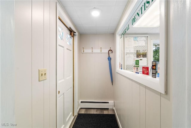 interior space with baseboard heating, wood walls, and wood-type flooring