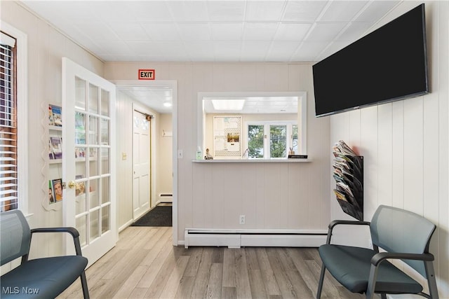 living area featuring wood walls, a baseboard heating unit, and light hardwood / wood-style flooring