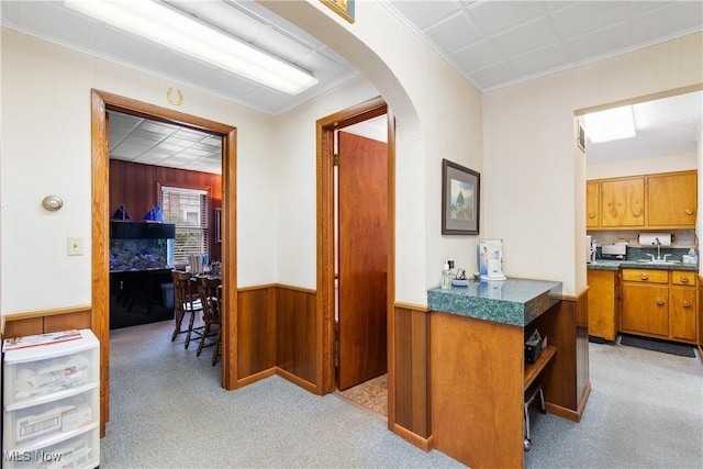 hallway with wood walls, light colored carpet, and ornamental molding