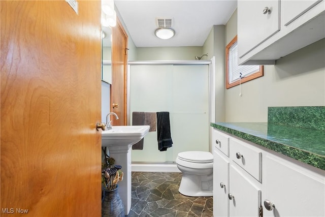 bathroom featuring toilet and a shower with shower door