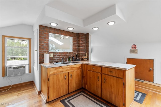 kitchen featuring kitchen peninsula, light wood-type flooring, vaulted ceiling, cooling unit, and sink