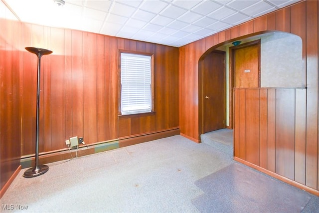 empty room featuring a drop ceiling and wood walls