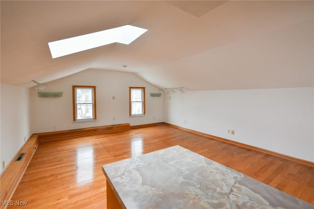 bonus room with lofted ceiling with skylight and light hardwood / wood-style floors