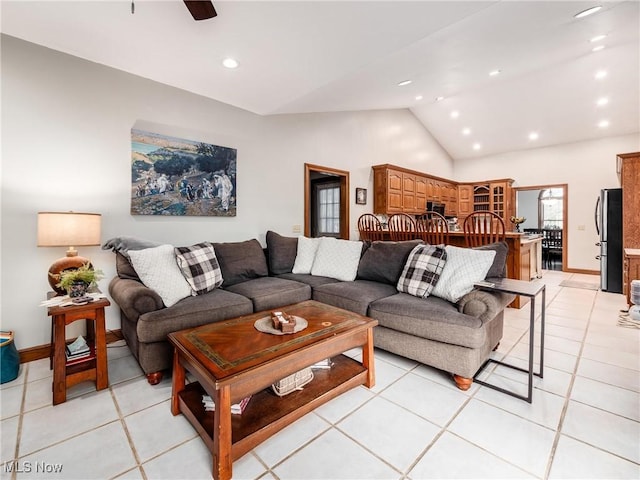 living room with ceiling fan, light tile patterned flooring, and vaulted ceiling