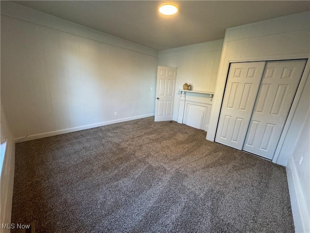 unfurnished bedroom featuring dark carpet and a closet