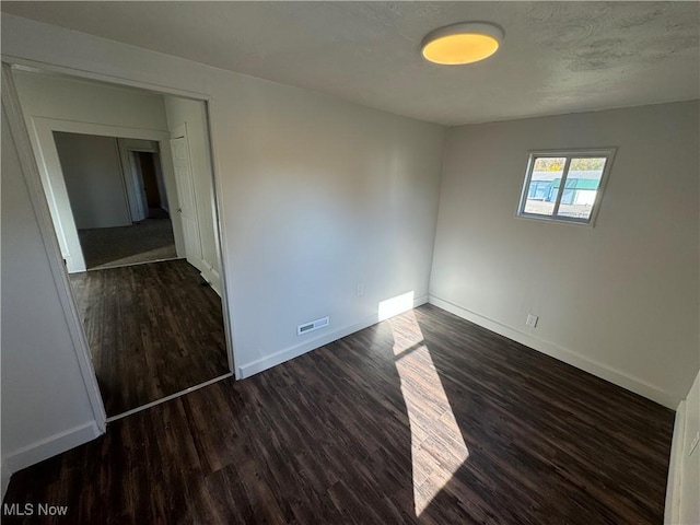 spare room featuring dark wood-type flooring