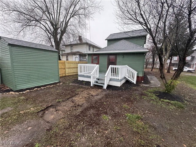 rear view of property featuring a storage unit and a deck