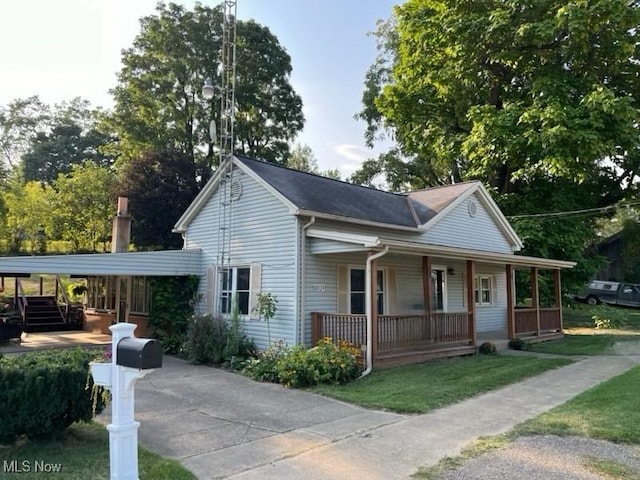 view of front of home featuring a carport, covered porch, and a front yard