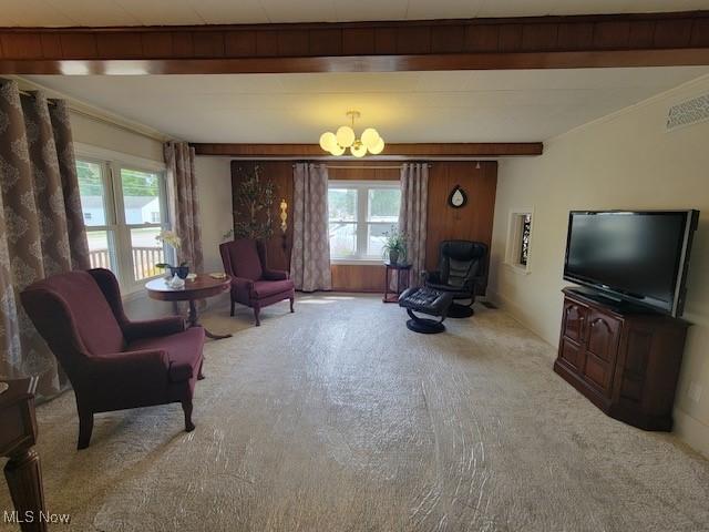 living area with a notable chandelier, ornamental molding, light carpet, and a wealth of natural light