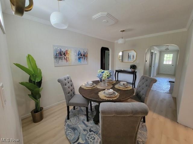 dining area with crown molding and light hardwood / wood-style flooring