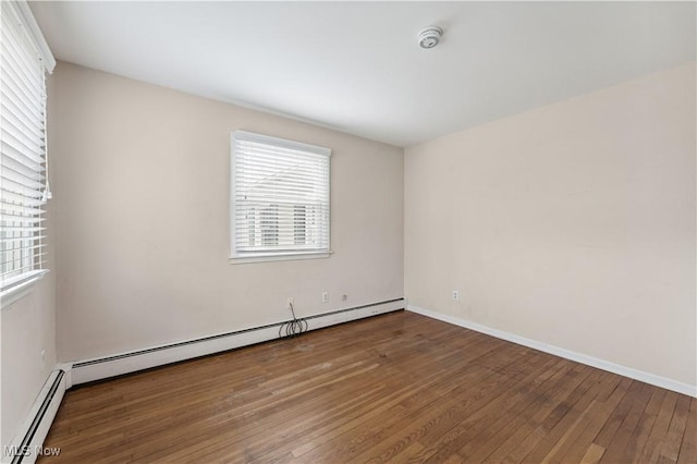 empty room with baseboard heating and hardwood / wood-style flooring