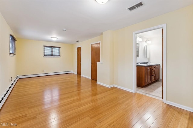 spare room featuring light hardwood / wood-style floors, sink, and a baseboard radiator