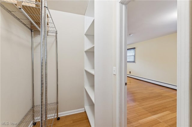 walk in closet featuring hardwood / wood-style floors and a baseboard heating unit