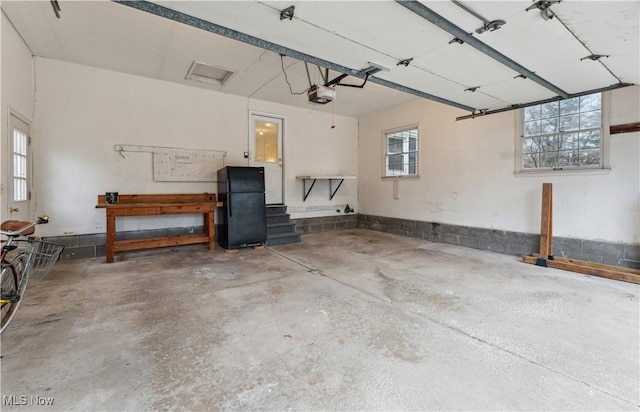 garage featuring black fridge and a garage door opener