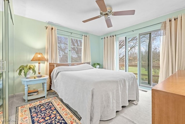 carpeted bedroom featuring access to exterior, multiple windows, and ceiling fan