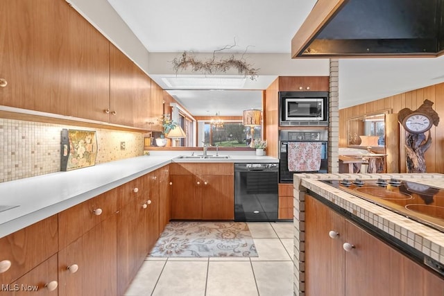 kitchen with sink, backsplash, a chandelier, light tile patterned floors, and black appliances