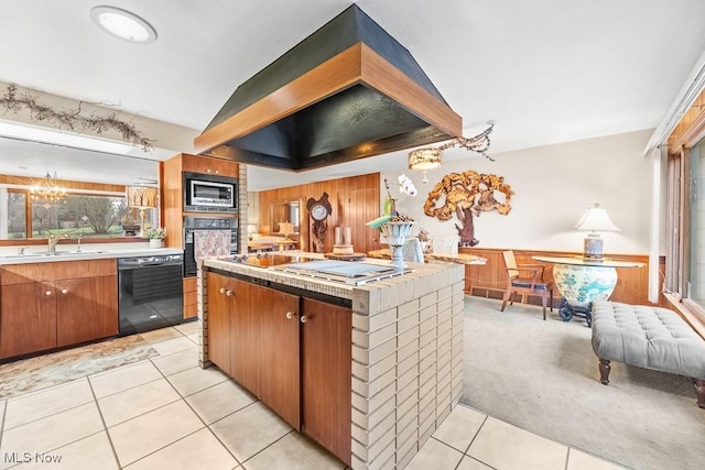 kitchen featuring light carpet, black appliances, sink, wooden walls, and custom range hood