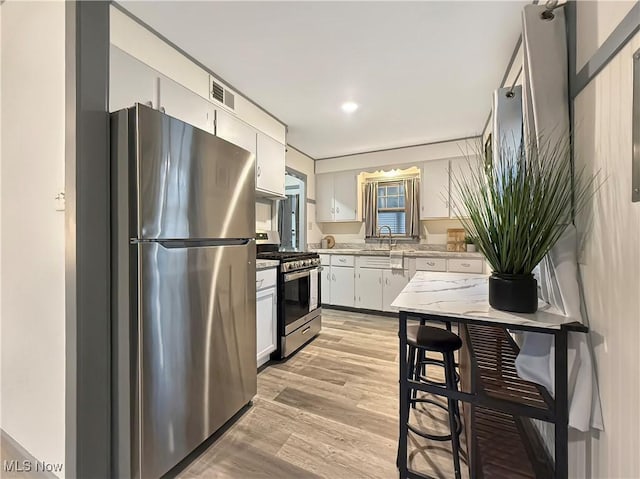 kitchen featuring sink, white cabinets, light wood-type flooring, and appliances with stainless steel finishes