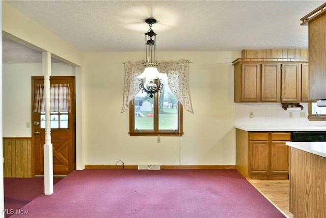 kitchen featuring backsplash, wooden walls, light hardwood / wood-style flooring, a textured ceiling, and decorative light fixtures