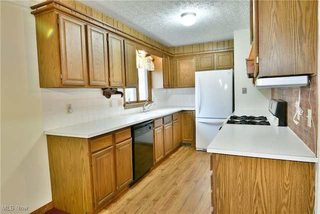 kitchen featuring light wood-type flooring, backsplash, a textured ceiling, white appliances, and sink