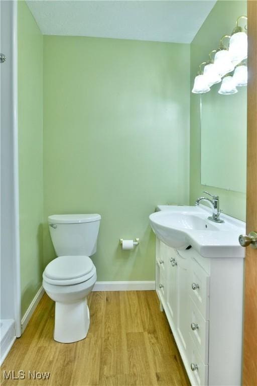 bathroom with wood-type flooring, vanity, and toilet