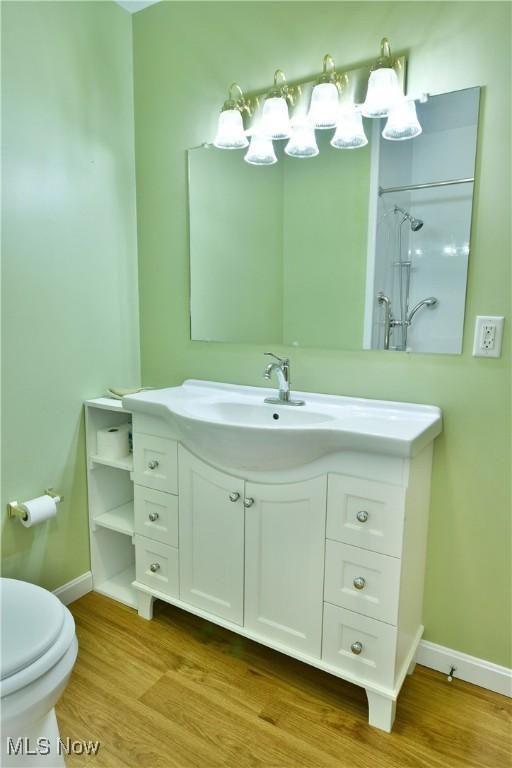 bathroom with a shower, hardwood / wood-style floors, vanity, and toilet