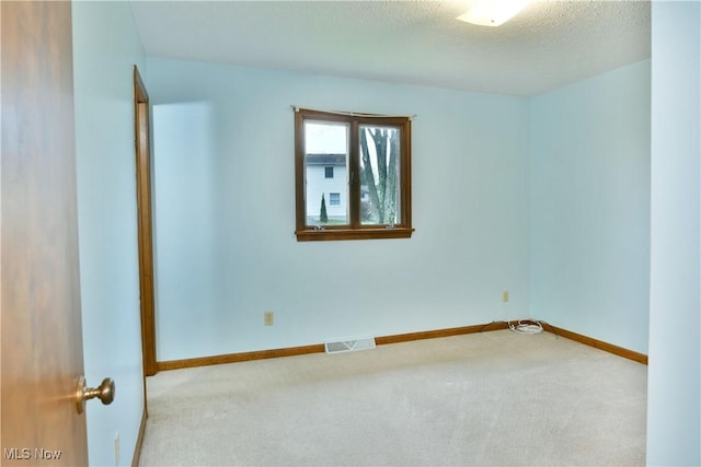 spare room with light carpet and a textured ceiling