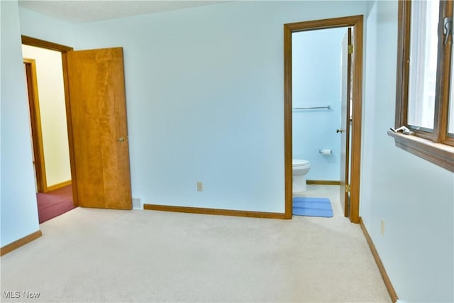 interior space featuring ensuite bath and light colored carpet