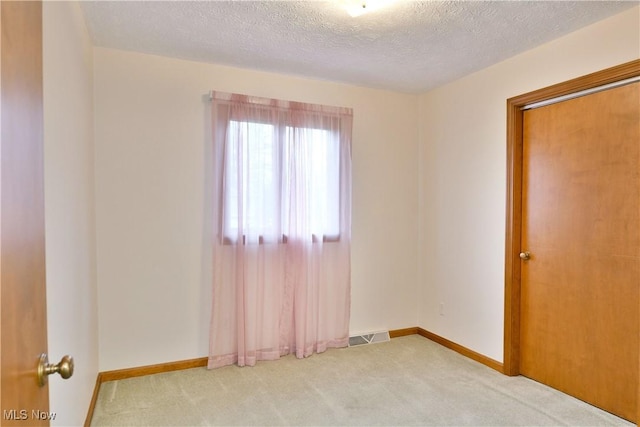 carpeted spare room featuring a textured ceiling