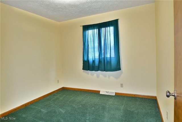 carpeted empty room featuring a textured ceiling