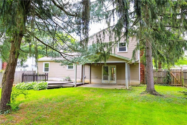 rear view of property featuring a yard, a patio, and a wooden deck