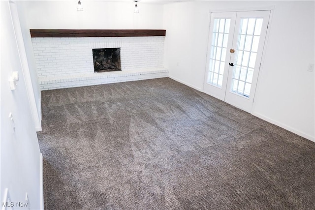 unfurnished living room featuring dark carpet, a fireplace, and french doors