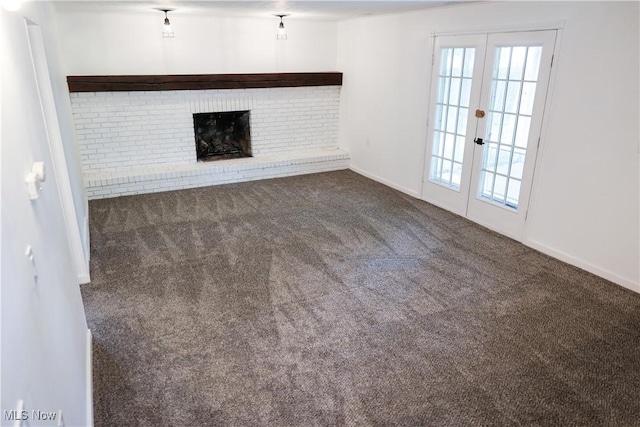 unfurnished living room with carpet flooring, a fireplace, and french doors