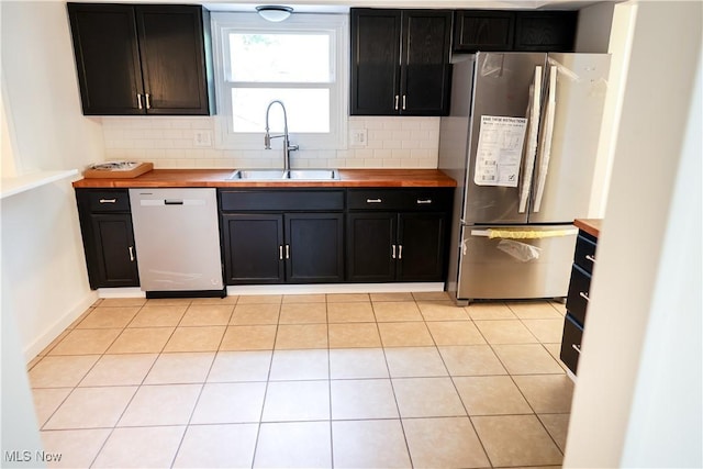 kitchen featuring dishwashing machine, decorative backsplash, sink, and stainless steel refrigerator