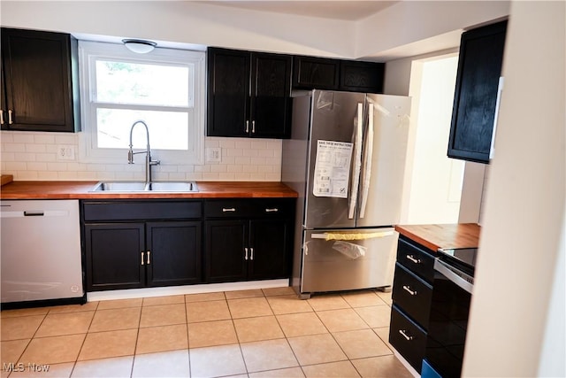 kitchen with butcher block countertops, backsplash, sink, and appliances with stainless steel finishes