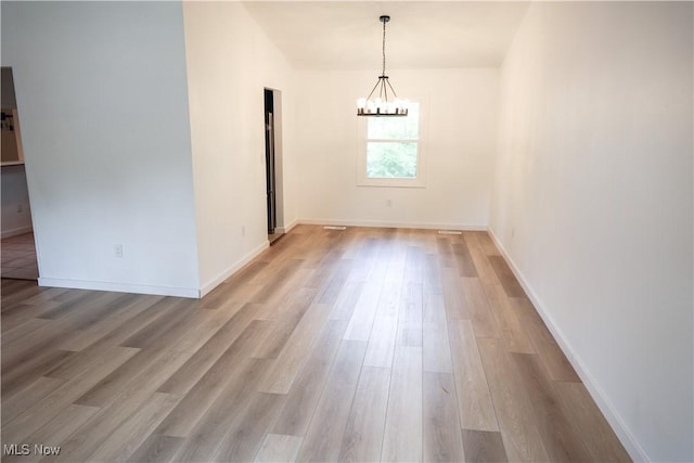 unfurnished dining area featuring a notable chandelier and light hardwood / wood-style flooring