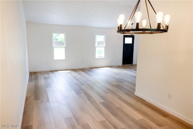 spare room featuring a notable chandelier and hardwood / wood-style flooring