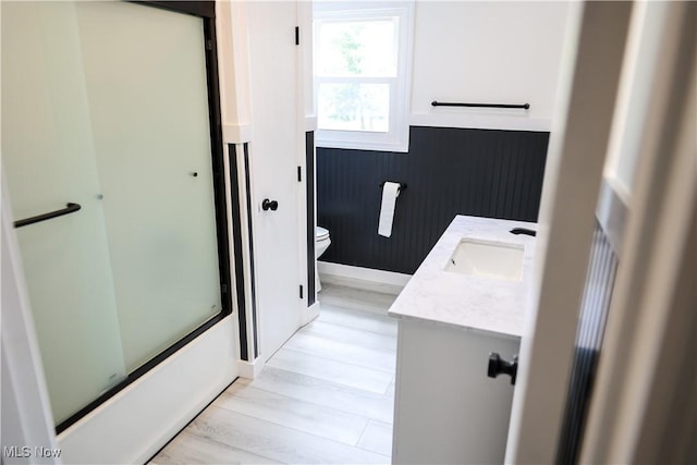 full bathroom featuring vanity, hardwood / wood-style flooring, toilet, and enclosed tub / shower combo