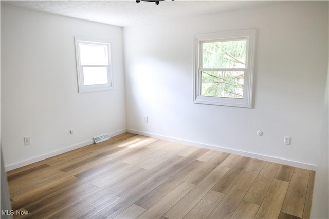 unfurnished room featuring light hardwood / wood-style flooring and a textured ceiling