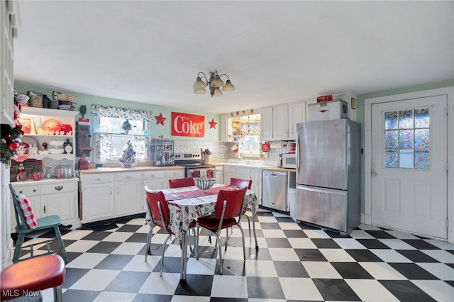 kitchen featuring stainless steel appliances, white cabinetry, a wealth of natural light, and a notable chandelier