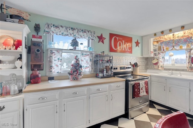 kitchen featuring electric range, decorative backsplash, white cabinetry, and a wealth of natural light